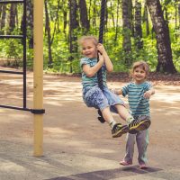 2 boys sitting on swing during daytime